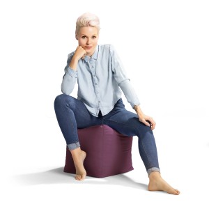 Frau sitzt auf einem auberginefarbenen Sitting Point Hocker (60 l).