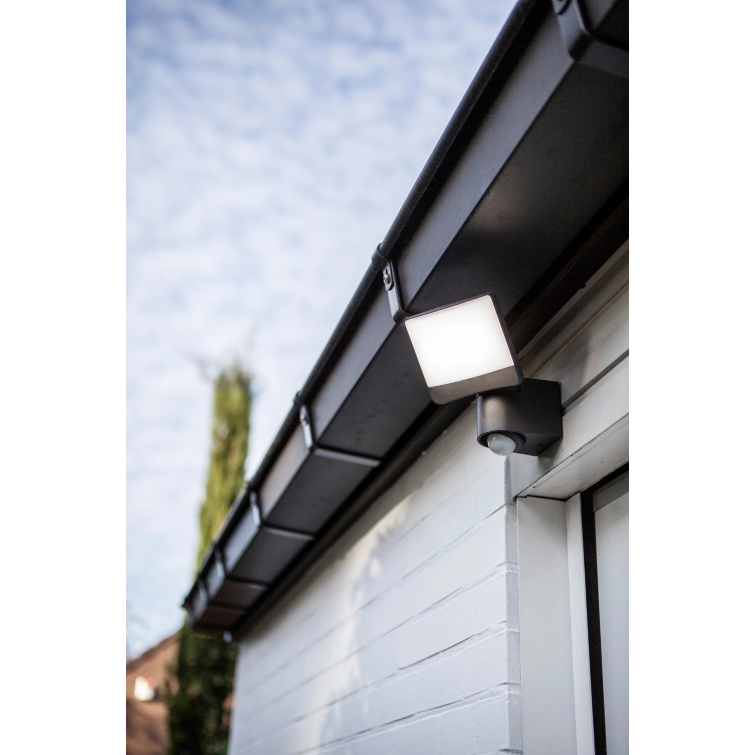 Lutec LED-Außenstrahler Sunshine mit schwenkbarem Kopf, montiert an einer Hauswand.