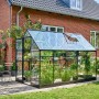 Schwarzes Halls Gewächshaus Qube 610 mit Glas und geöffnetem Dachfenster im Garten.