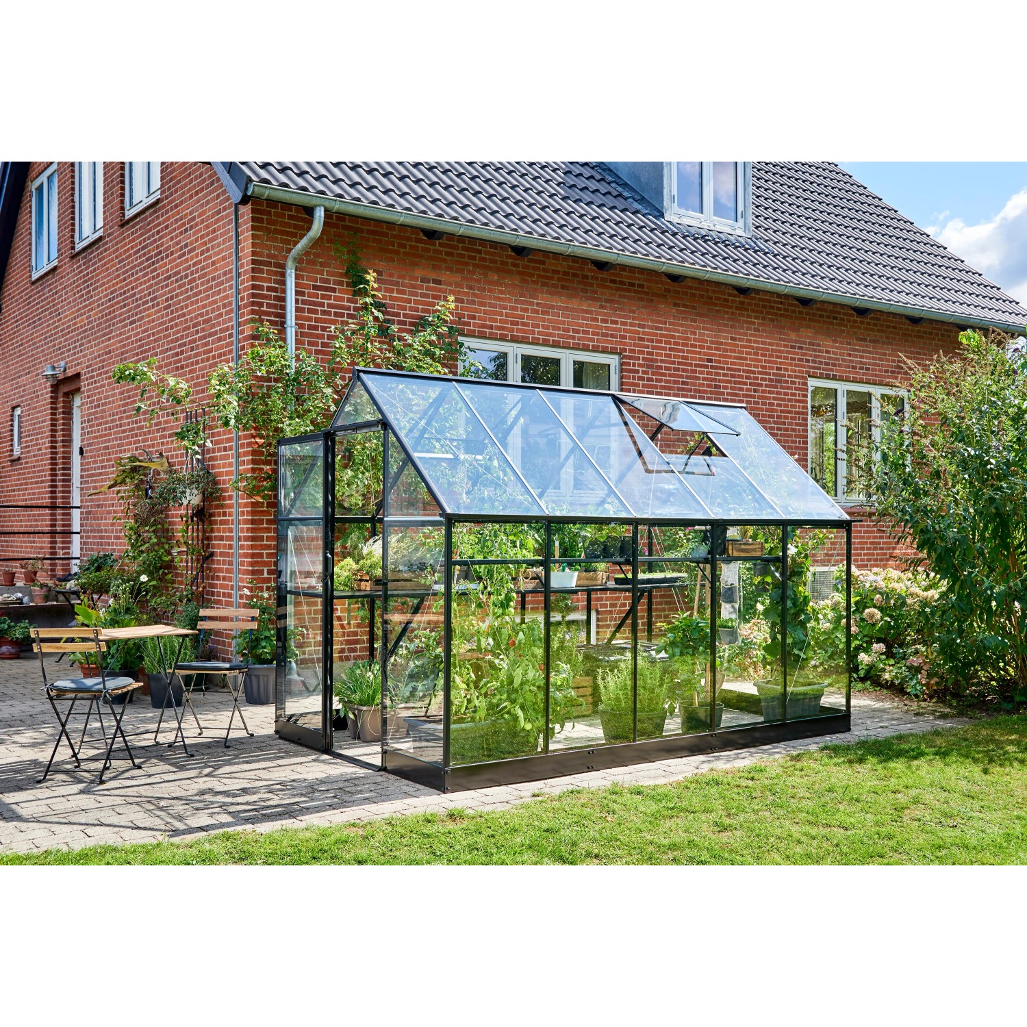 Schwarzes Halls Gewächshaus Qube 610 mit Glas und geöffnetem Dachfenster im Garten.