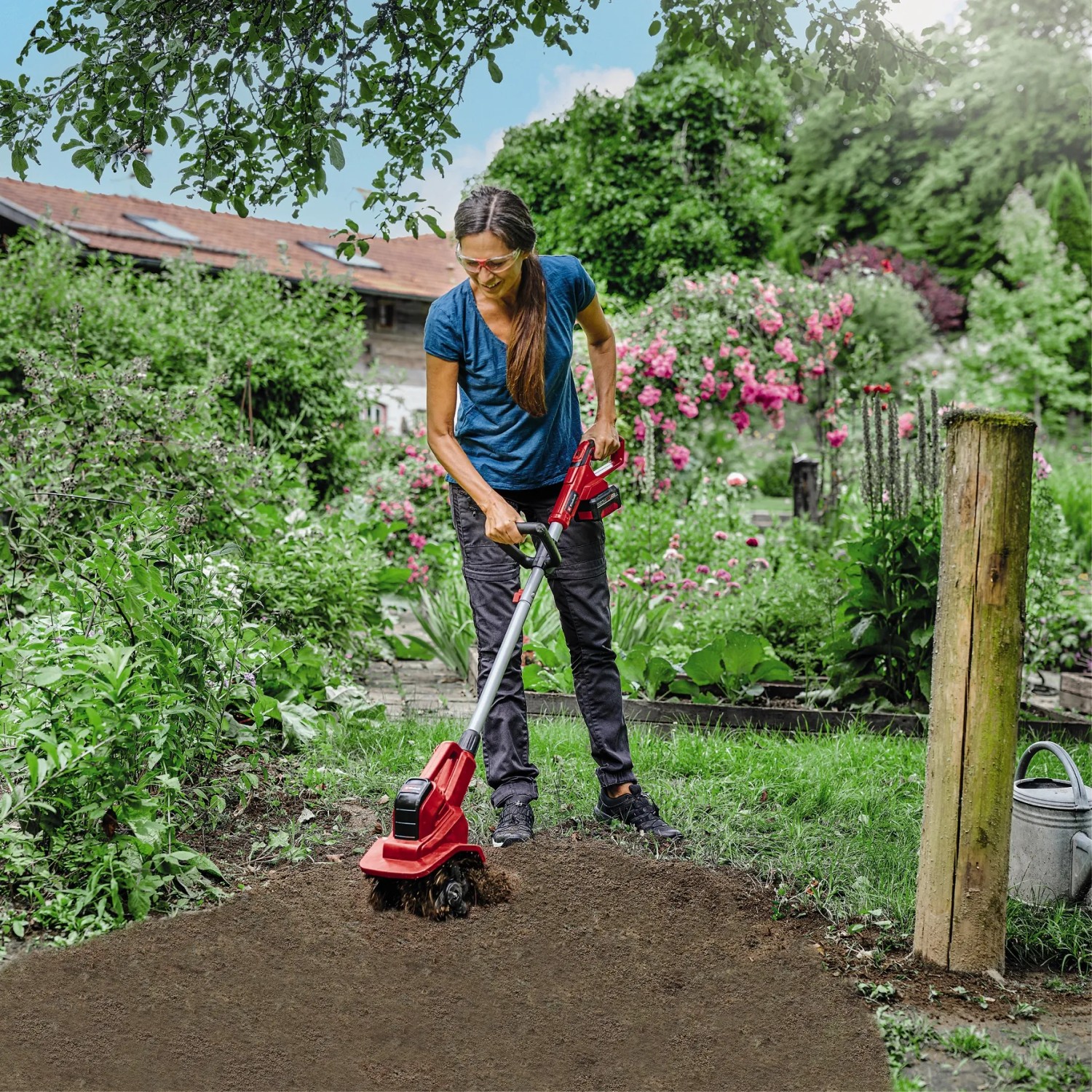 Frau arbeitet mit der roten Einhell Akku-Bodenhacke GE-CR 18/20 Li E im Garten.