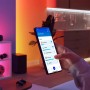 Hand steuert Philips Smart GU10 RGB Einbauspot Beleuchtung per App. Smarte Leuchtmittel mit farbigem, dimmbarem Licht im Raum.