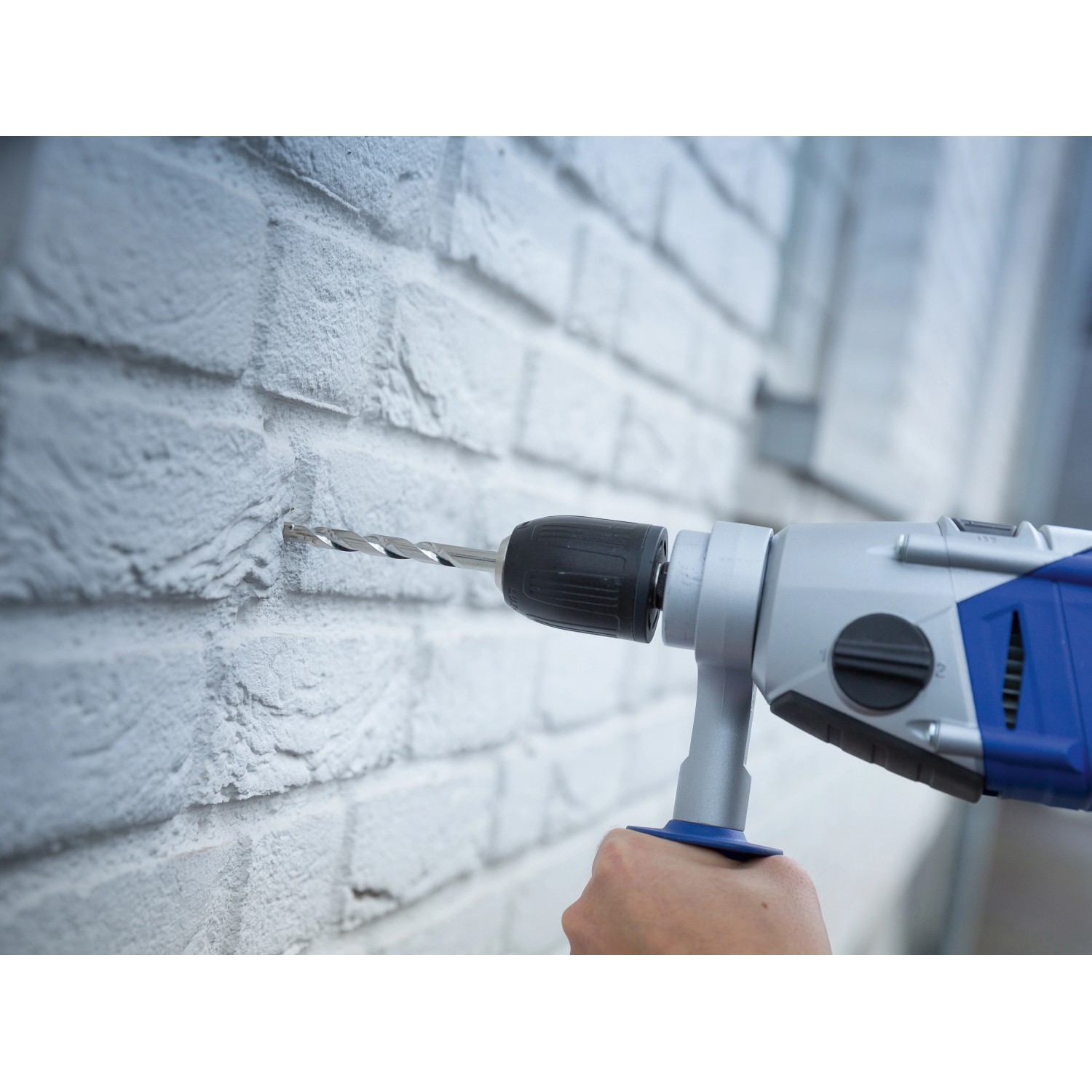 LUX Steinbohrer bohrt Loch in weiße Ziegelwand mit Schlagbohrmaschine.