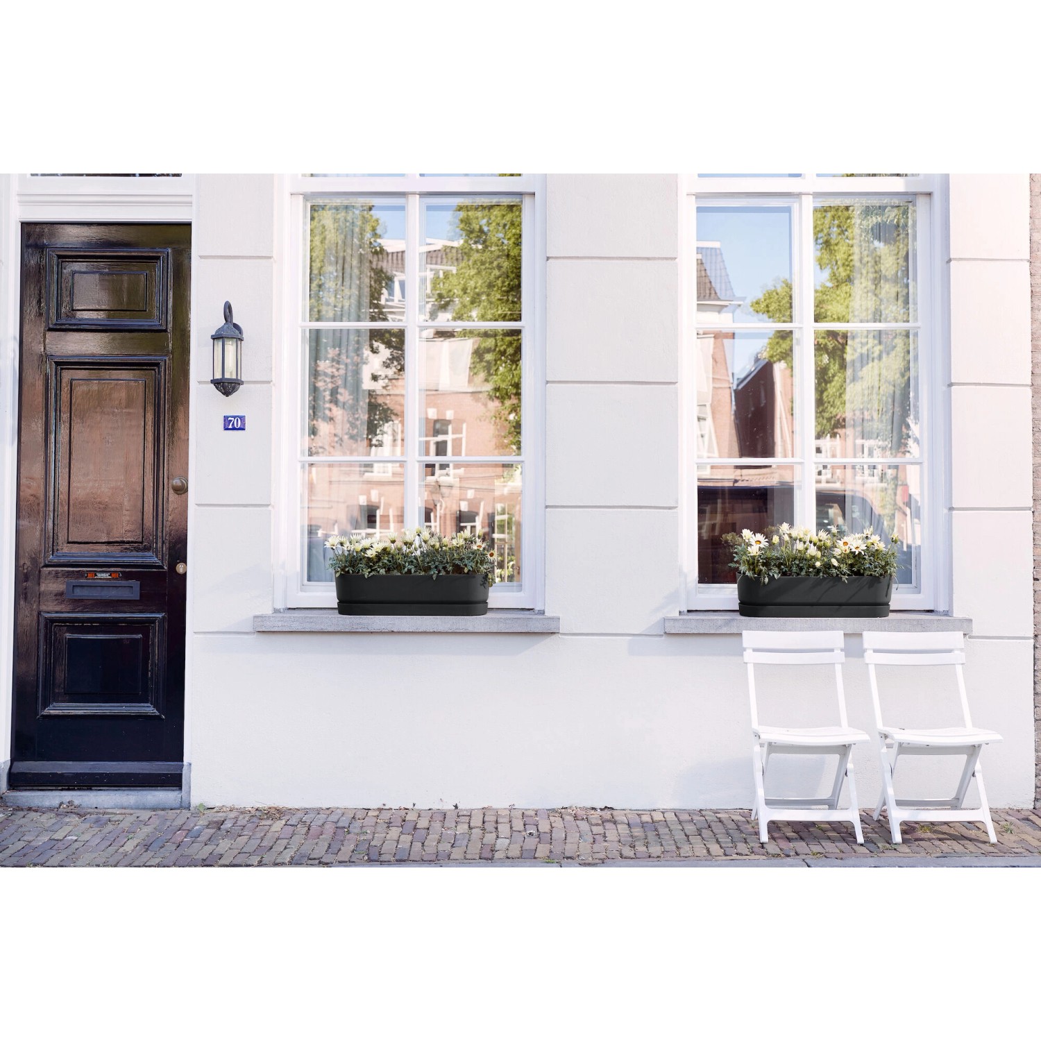 Elho Greenville Blumenkasten in Schwarz, 69 cm, auf einer Fensterbank mit weißen Blumen.