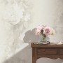 Beige Vliestapete Aurora Lucent Bloom mit floralem Muster an einer Wand.