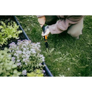 Person entfernt Unkraut mit Fiskars OneClick Unkrautstecher im Garten.