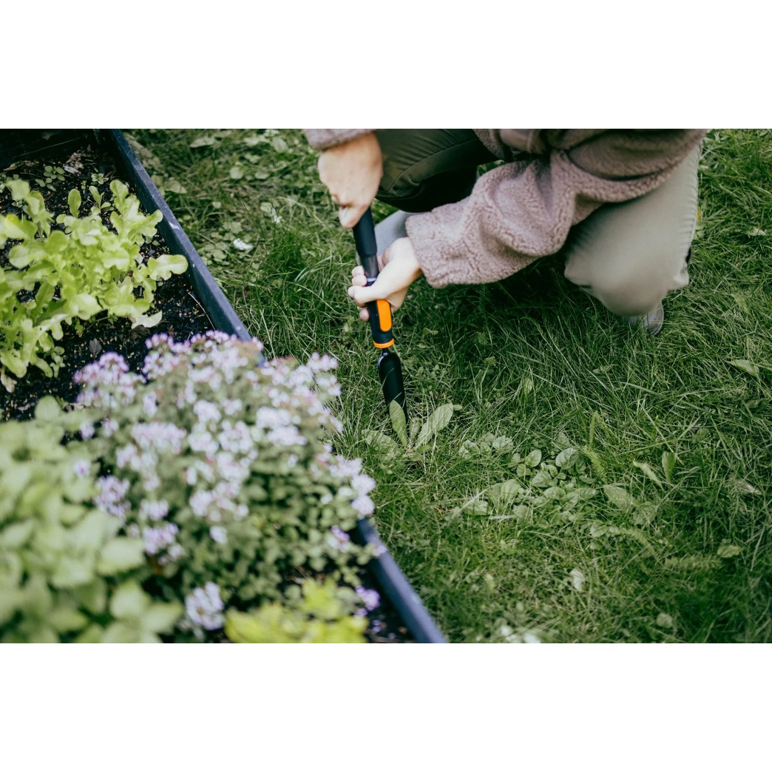 Person entfernt Unkraut mit Fiskars OneClick Unkrautstecher im Garten.