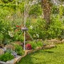 Gardena Regner-Stativ im Garten, bewässert Blumen und Pflanzen. Dreibein-Stativ für Regner.