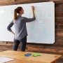 Frau schreibt auf Whiteboard mit bunten Relaxdays Whiteboard Schwämmen auf Tisch im Vordergrund.