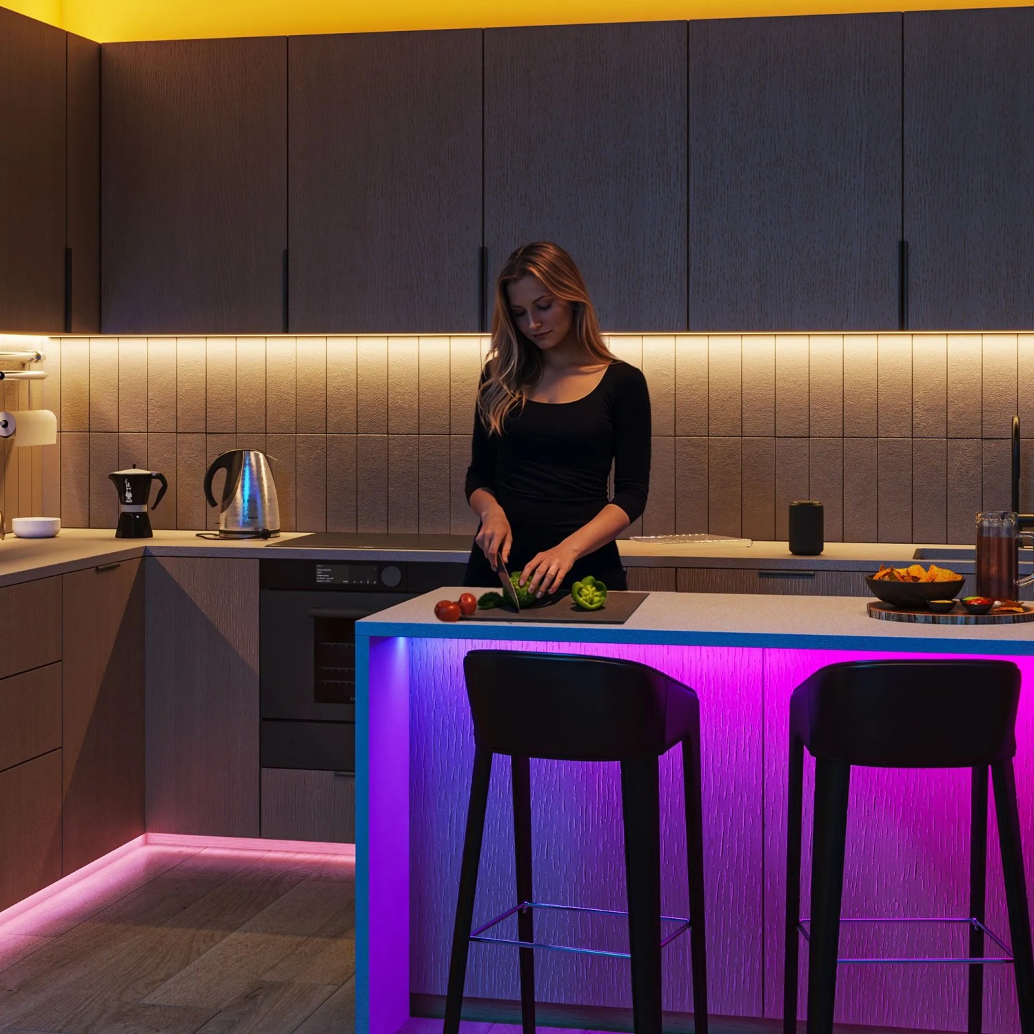 Küche mit Philips Smart-LED-Licht. Frau kocht, farbige und warmweiße Beleuchtung für individuelle Stimmung.