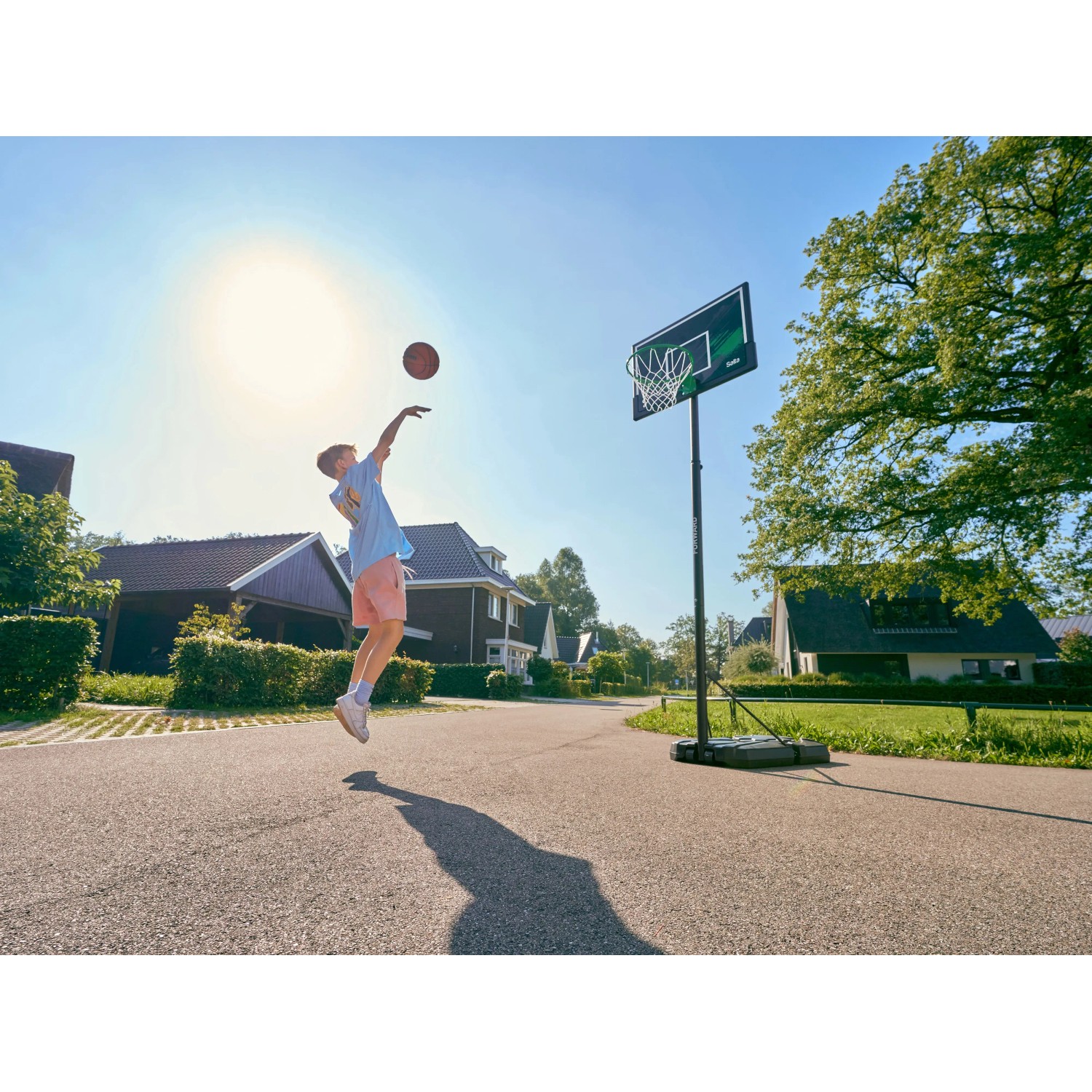 Junge wirft Ball auf Salta Basketballständer Forward (108x362cm) im Garten.