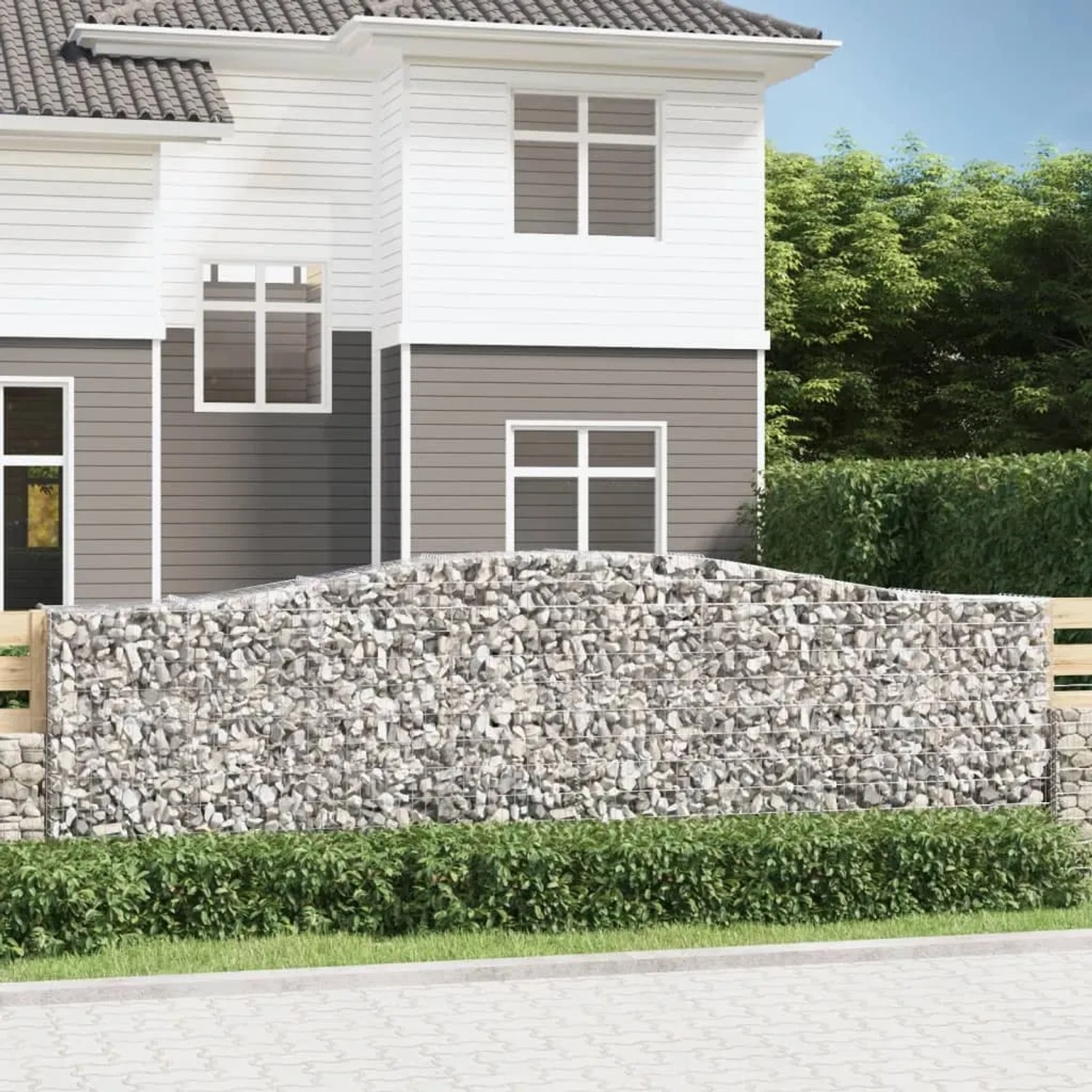 Gabionen-Hochbeet mit Bogen, gefüllt mit Steinen, als dekorative Gartenmauer vor einem Haus.