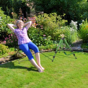 Relaxdays Kreisregner aus Metall, grün, mit Stativ im Garten. Frau entspannt daneben.