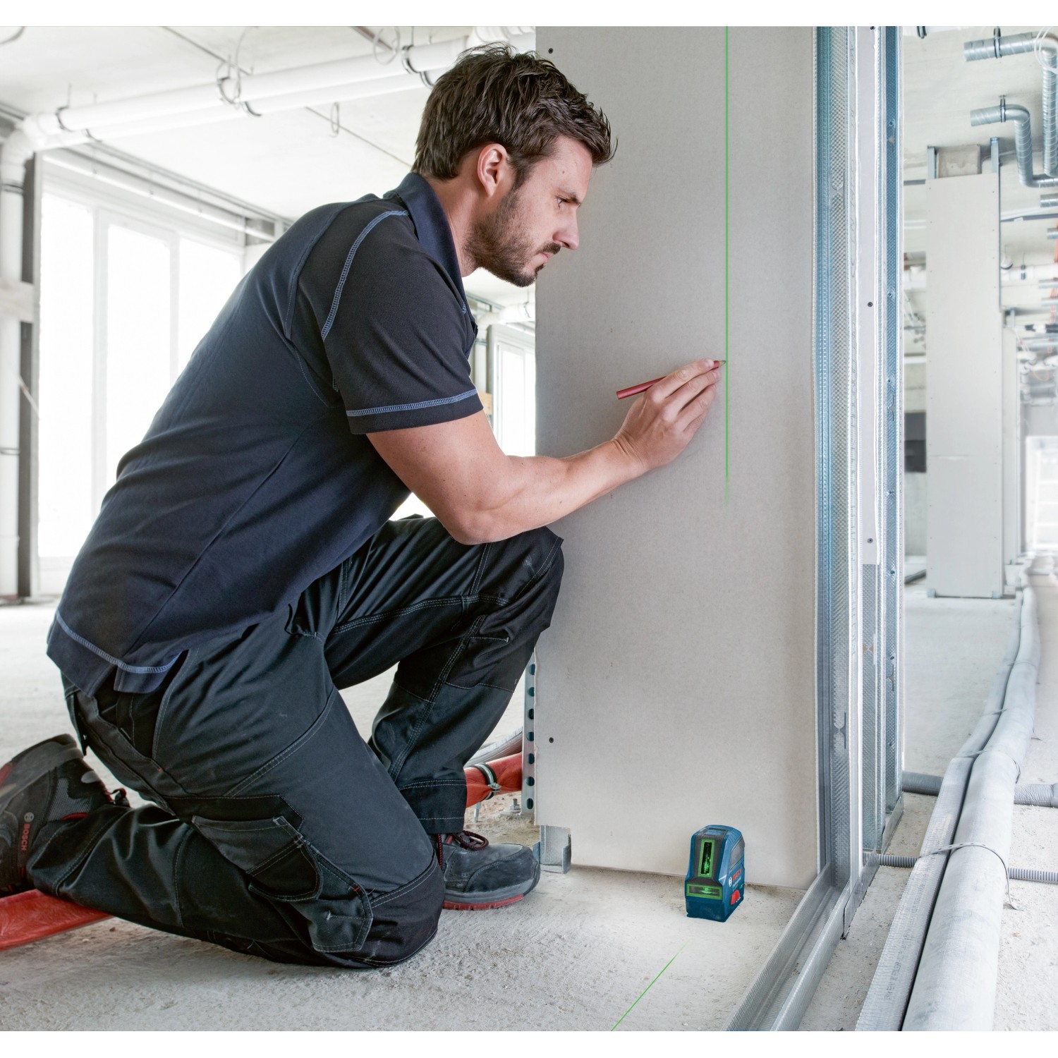 Handwerker markiert Linie mit Bosch Professional GLL 2-10 Kreuzlinienlaser an Wand.