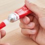 Hände öffnen rote Tube Fischer 30 Sekunden Kleber 15g. Sekundenkleber und Verschluss sind zu sehen.