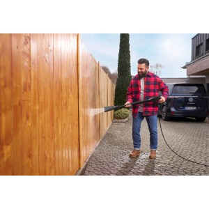 Mann reinigt Holzzaun mit Kärcher eco!Booster 120 Strahlrohr für Hochdruckreiniger K2/K3.