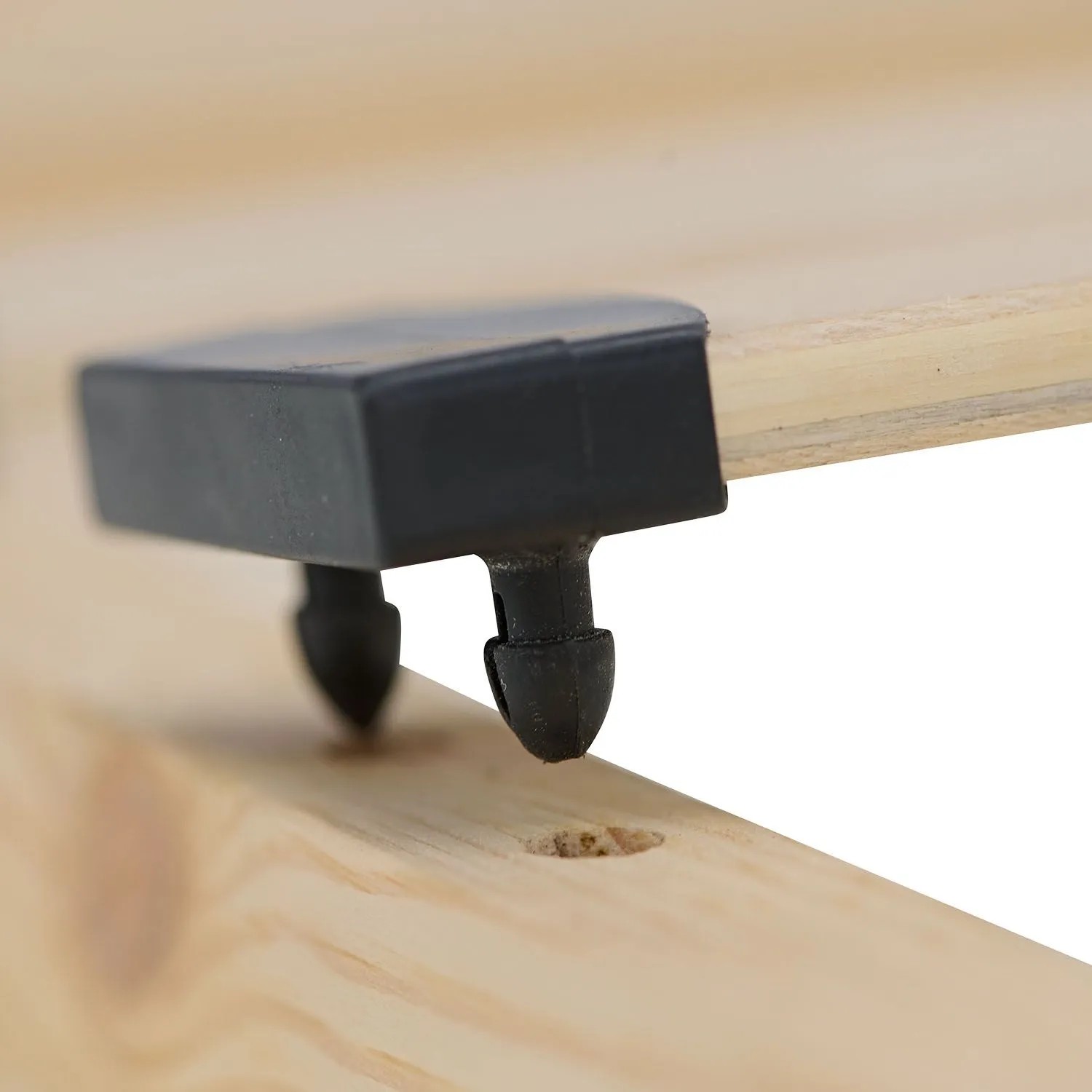 Nahaufnahme einer schwarzen Kunststoffkappe, die eine Federholzleiste am Lattenrost 90x200 aus Holz befestigt.