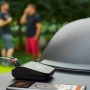 Weber Connect Smart Grilling Hub Grillthermometer mit 2 Fühlern auf Grill, Smartphone im Vordergrund.