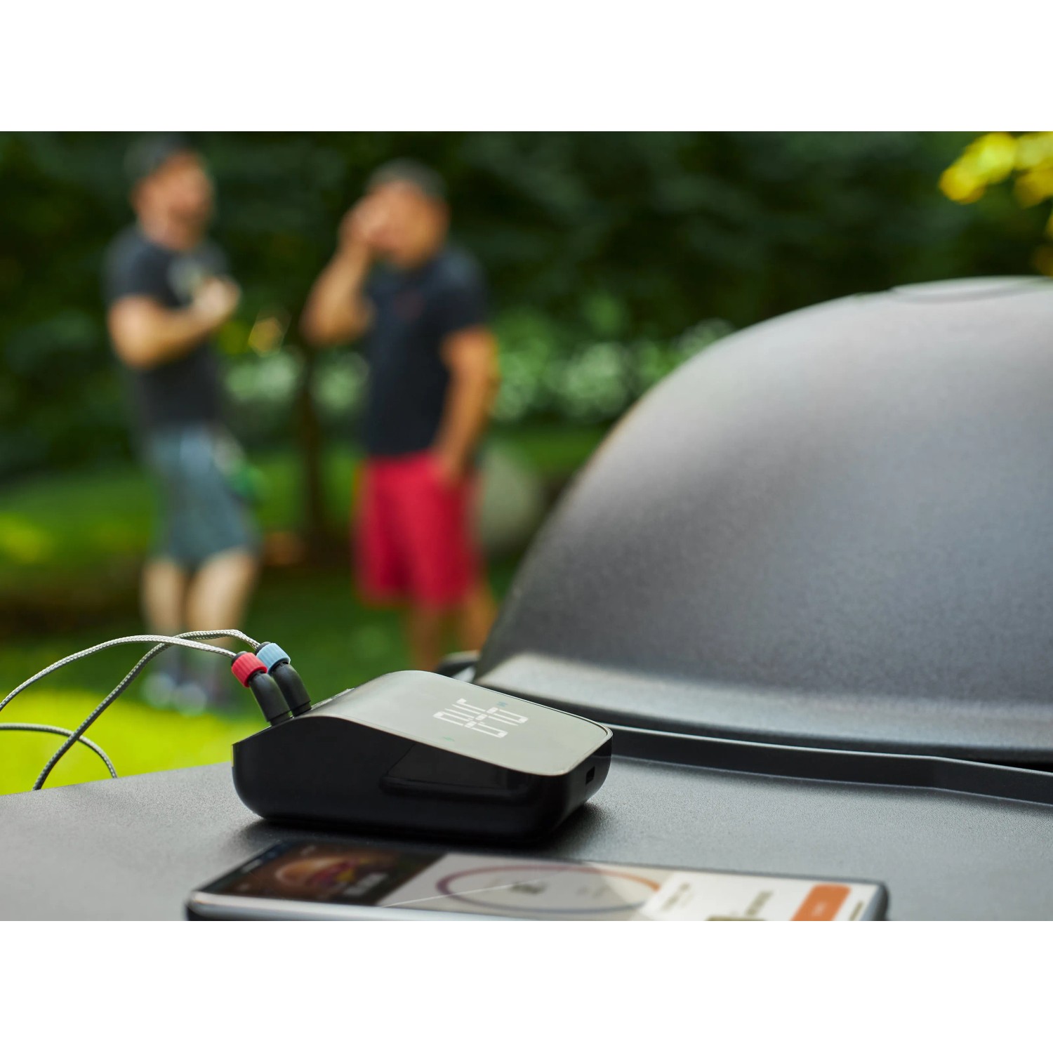 Weber Connect Smart Grilling Hub Grillthermometer mit 2 Fühlern auf Grill, Smartphone im Vordergrund.