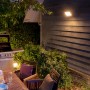 Philips Hue Discover LED-Wandleuchte beleuchtet Terrasse mit Grill und Sitzgruppe.