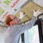Mann montiert Rockwool Formrock Untersparrendämmung (60mm) zwischen Sparren. Mineralfaser Dämmstoff.