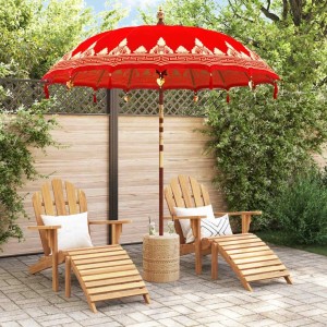 Roter balinesischer Sonnenschirm mit goldenen Mustern, Quasten und Glocken auf einer Terrasse mit Holzstühlen.