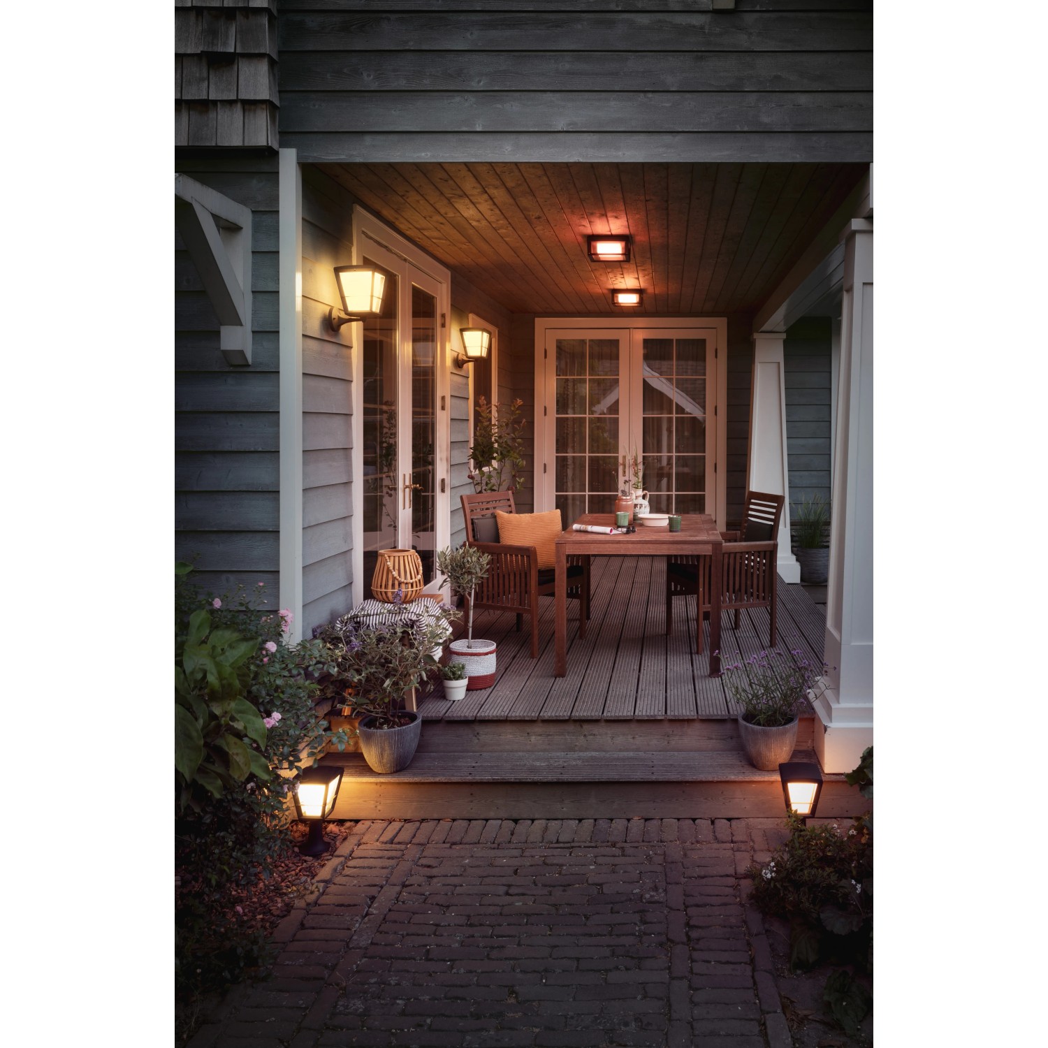 Beleuchtete Terrasse mit Philips Hue Econic Sockelleuchten und Wandleuchten in warmem Licht.