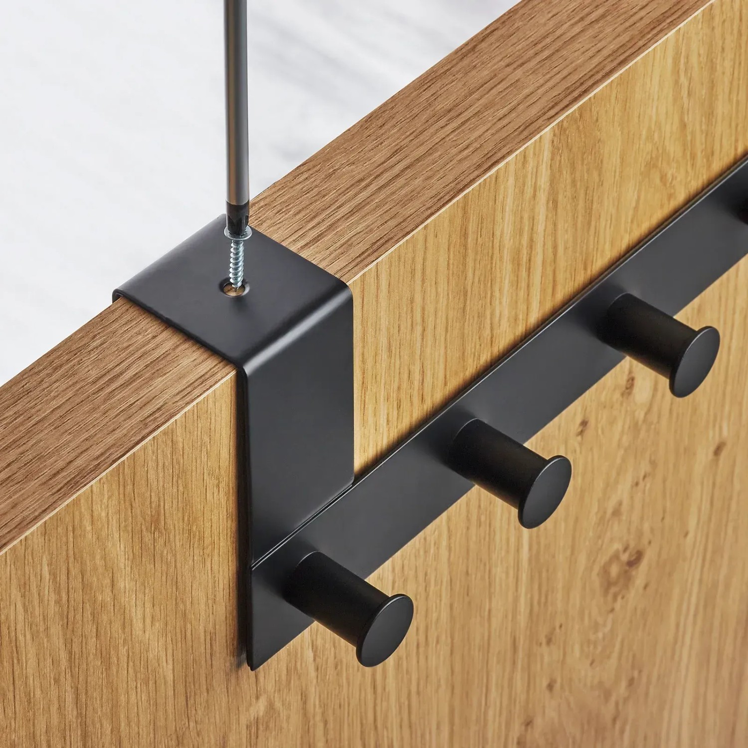 Schwarze SOTECH Türgarderobe LINEA II aus Edelstahl mit 6 Haken, wird auf Holztür fixiert.
