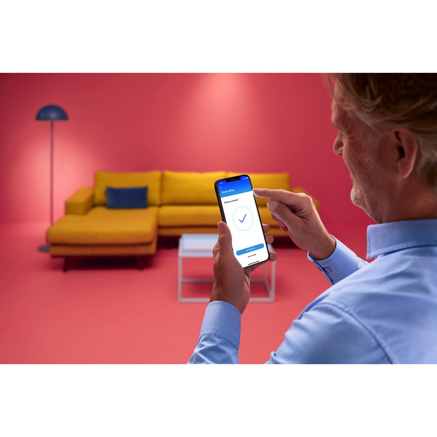 Mann steuert WiZ LED-Panel per App. Smarte Leuchte mit tunable white Funktion im Wohnraum.