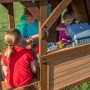 Kinder spielen im unteren Bereich des Backyard Discovery Cedar Cove Spielturms mit Spielküche und Grill.
