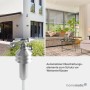 Silberner Homematic IP Wettersensor basic im Garten. Daneben Wohnzimmer mit Jalousien. Hausautomation für Wetterschutz.