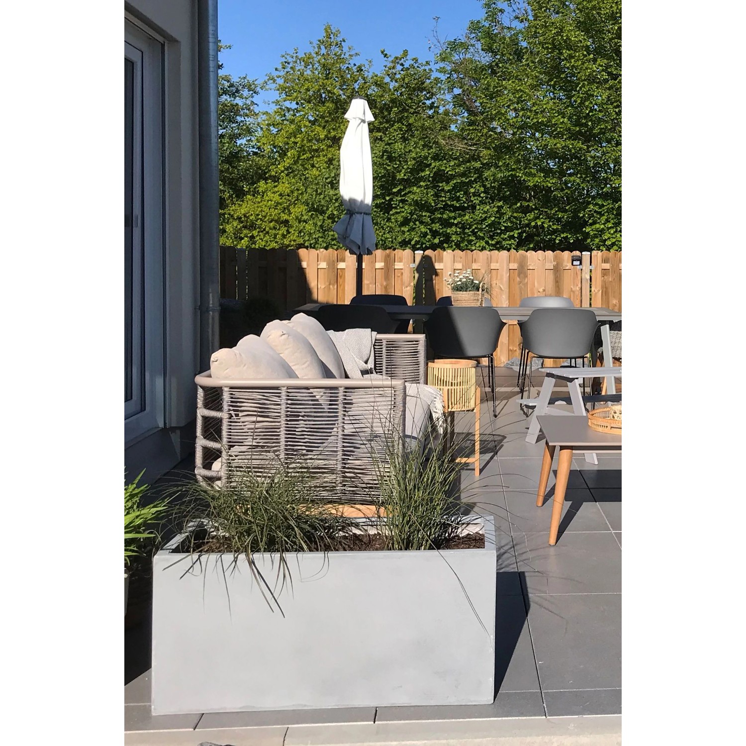 Grauer Vivanno Pflanzkübel Maxi in Betonoptik (80x40x40 cm) auf einer Terrasse.