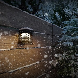 Schwarze Philips Solar-Außenwandleuchte Hara an einer Holzwand im Schnee.