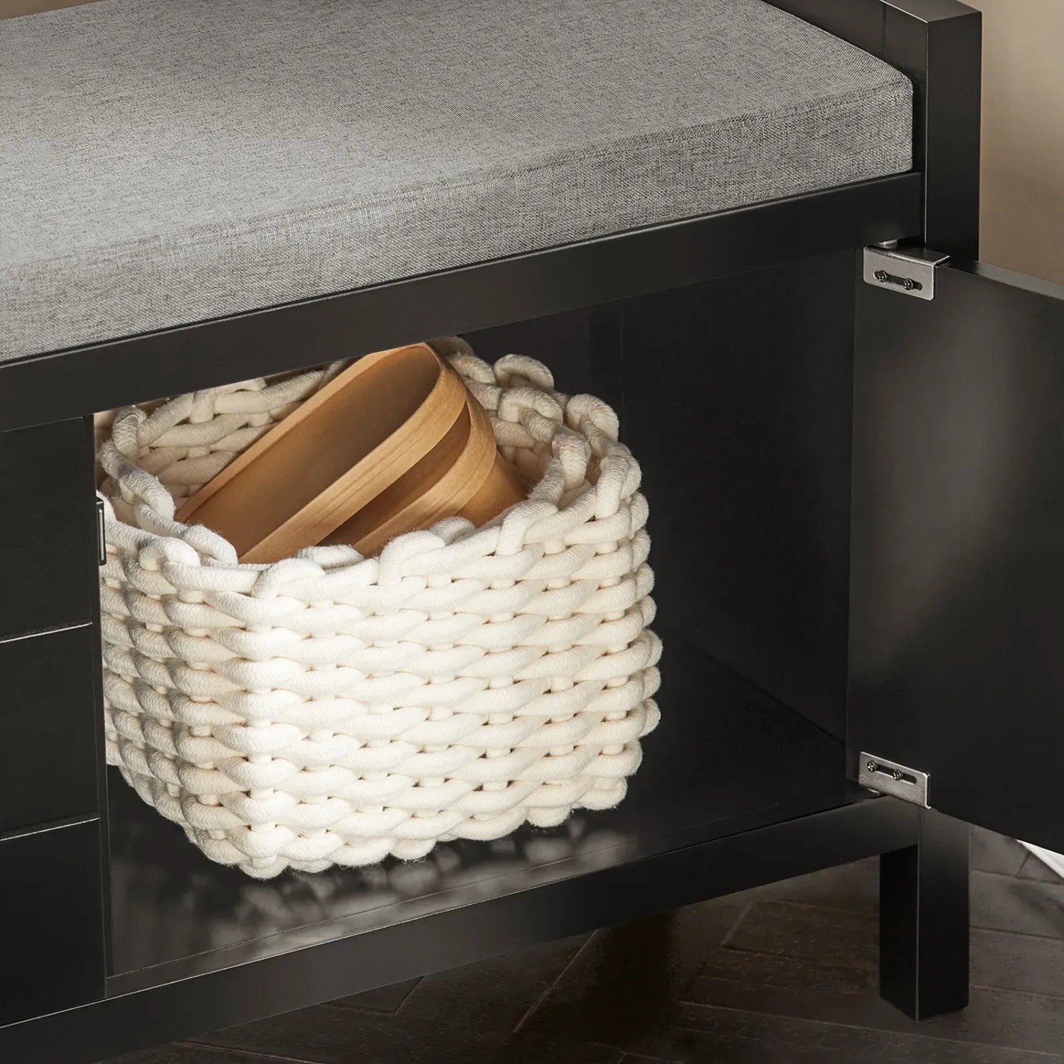 Schwarze Schuhbank mit grauer Sitzfläche und Stauraum für Schuhe.