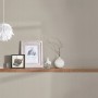 Beige-braune Vliestapete Uni (FSC®) an Wand mit Deko-Elementen auf Holzregal.