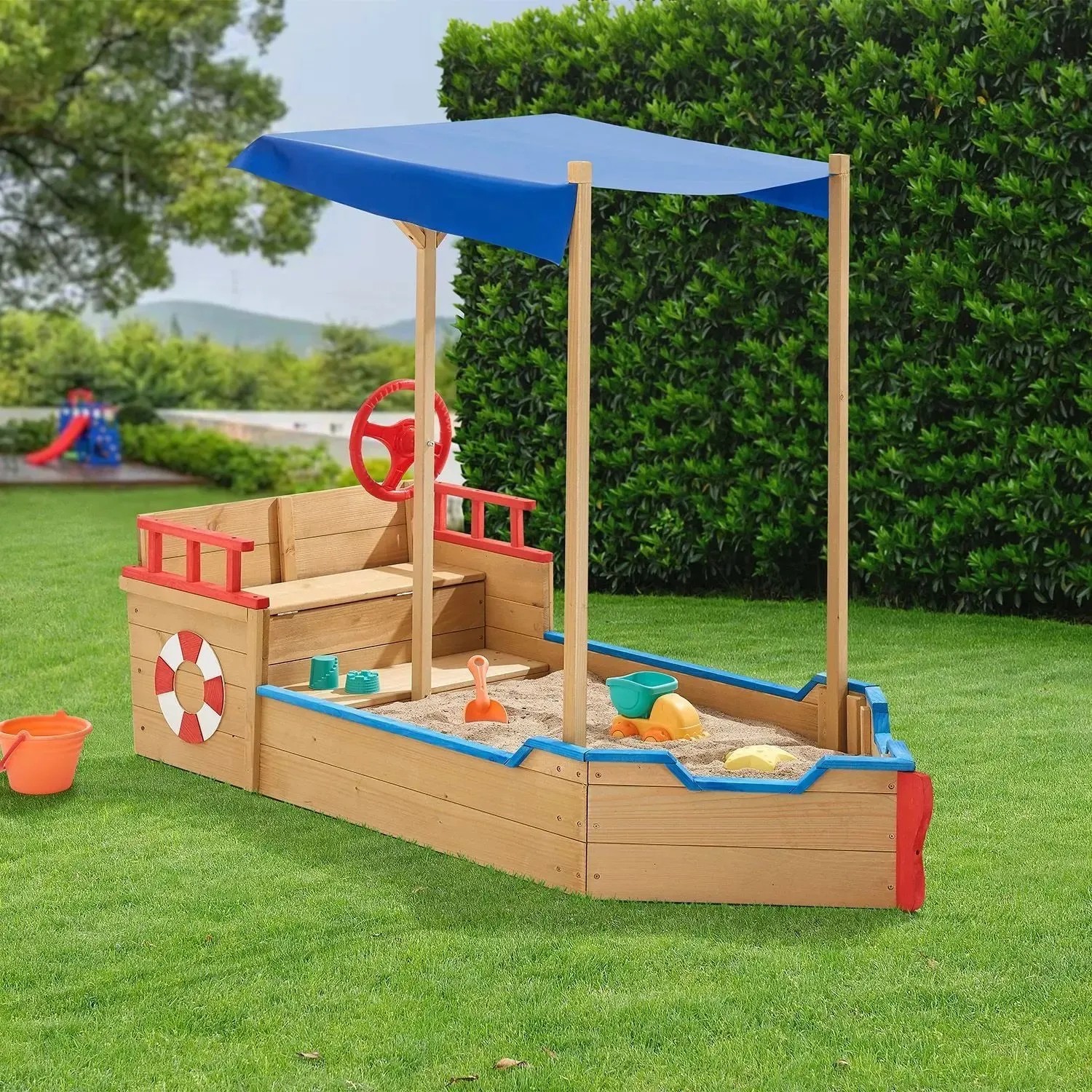 Juskys Sandkasten Käpt n Pit Piratenschiff aus Holz mit blauem Sonnensegel im Garten.