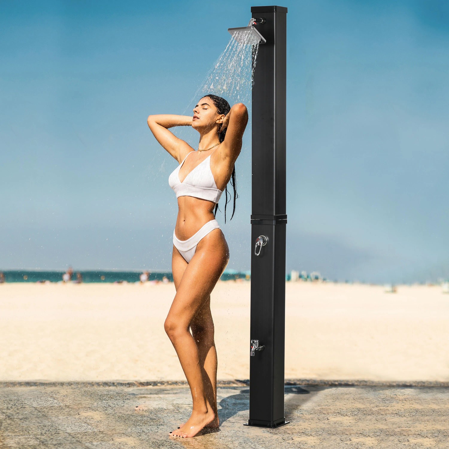 Outsunny Solardusche aus ABS und Zinklegierung, schwarz, mit Frau unter der Dusche am Strand.
