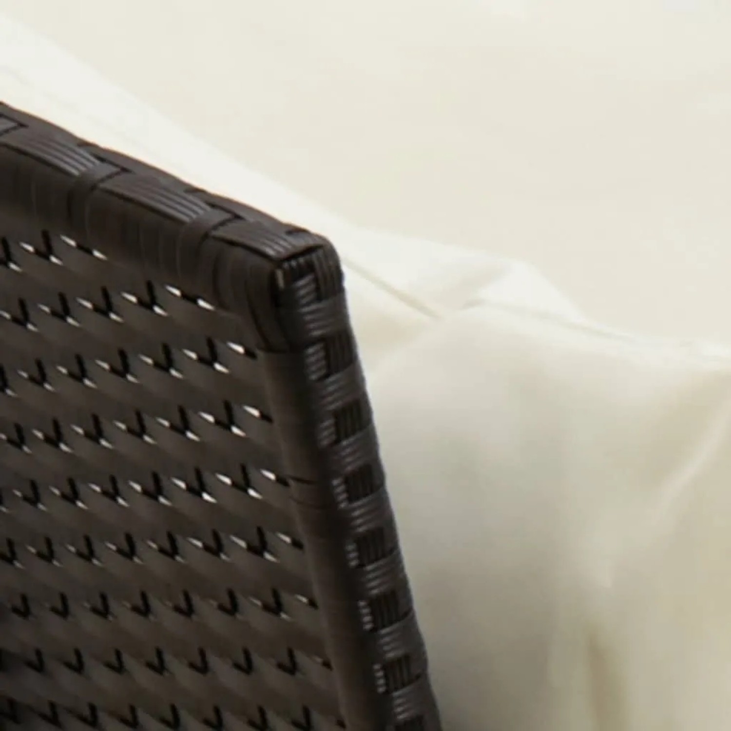 Detailaufnahme: Schwarze Rattan Garten-Sofagarnitur mit cremefarbenen Kissen.