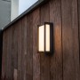 Moderne Lutec LED-Außenwandleuchte Qubo an einer Holzwand. Quadratische Form, warmweißes Licht.