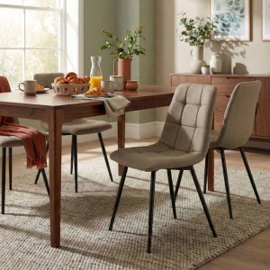 4er Set Esszimmerstühle Antibes in Taupe Stoff, gesteppt, mit schwarzen Metallbeinen an einem Holztisch.