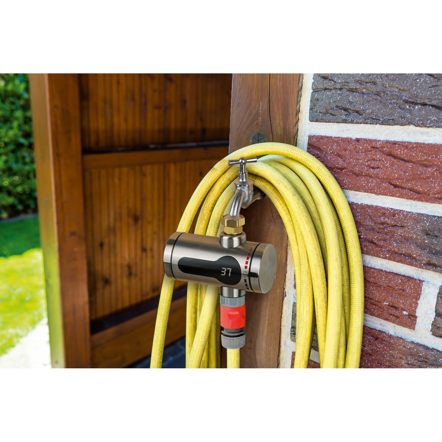 Maxxmee Edelstahl Durchlauferhitzer 3600W am Wasserhahn mit gelbem Gartenschlauch.