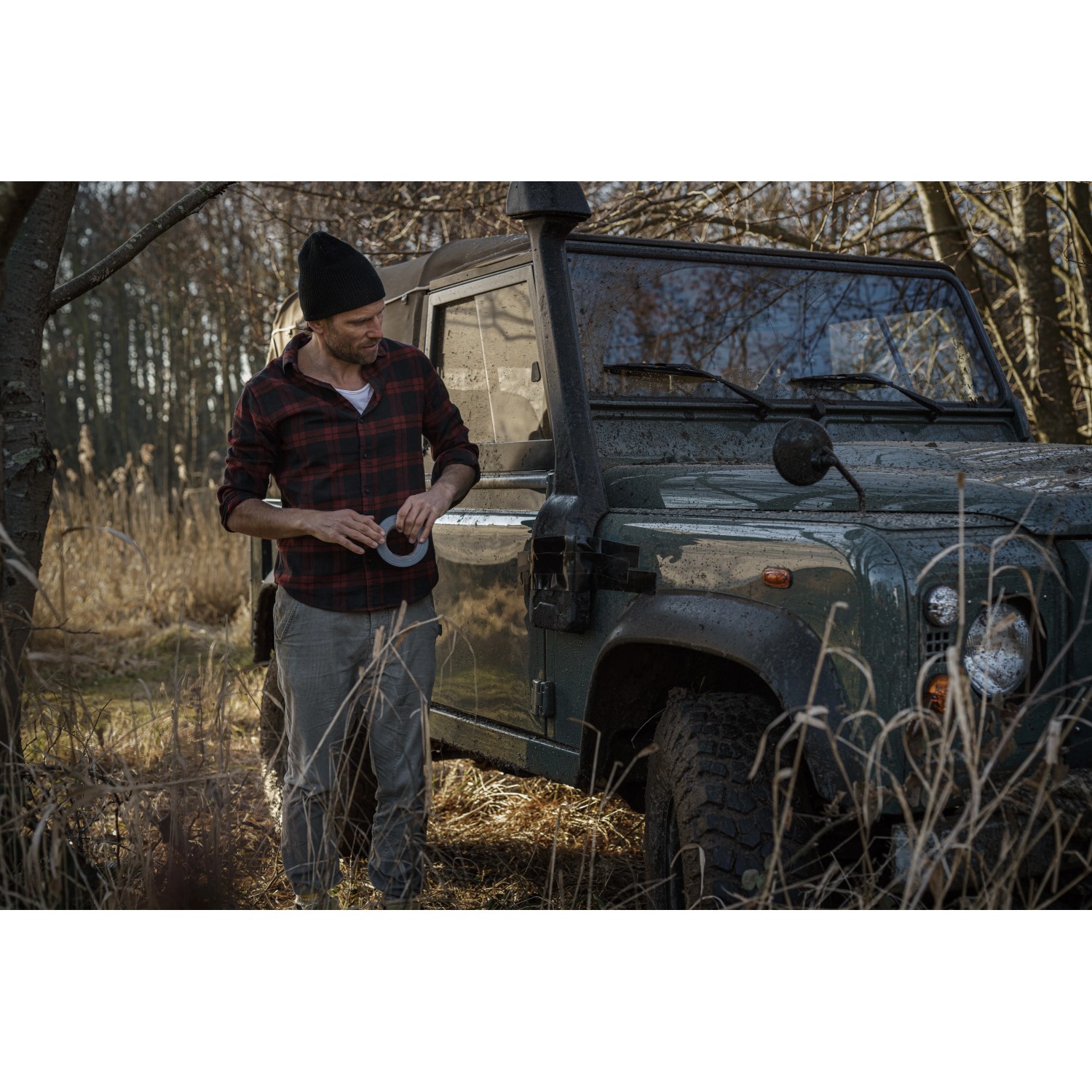 Mann mit Tesa Reparaturband Ultra Power Extreme vor Geländewagen in der Natur.