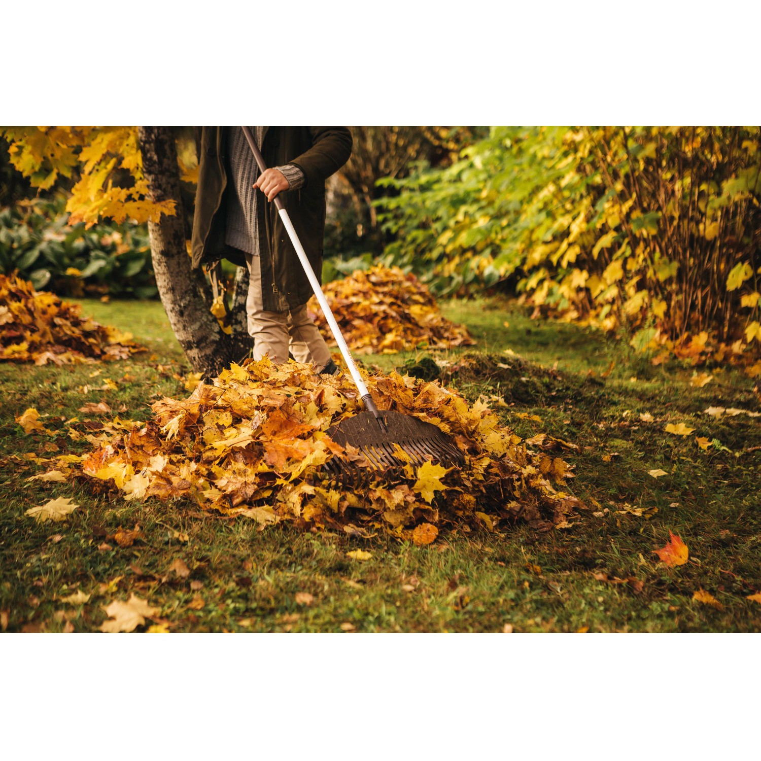 Person harkt Laub mit Fiskars Light Laubbesen. Leichter Aluminium-Stiel, flexible Zinken.