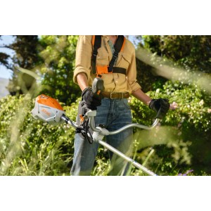 Person mäht mit orange-grauer Stihl Akku-Motorsense FSA 80 mit Zweihandgriff und Tragegurt im Garten.