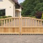 Gebogenes Doppeltor aus hellem Lärchenholz, 300 cm breit, als Vorgartenzaun vor einem Haus. Unten blickdicht, oben mit Latten.