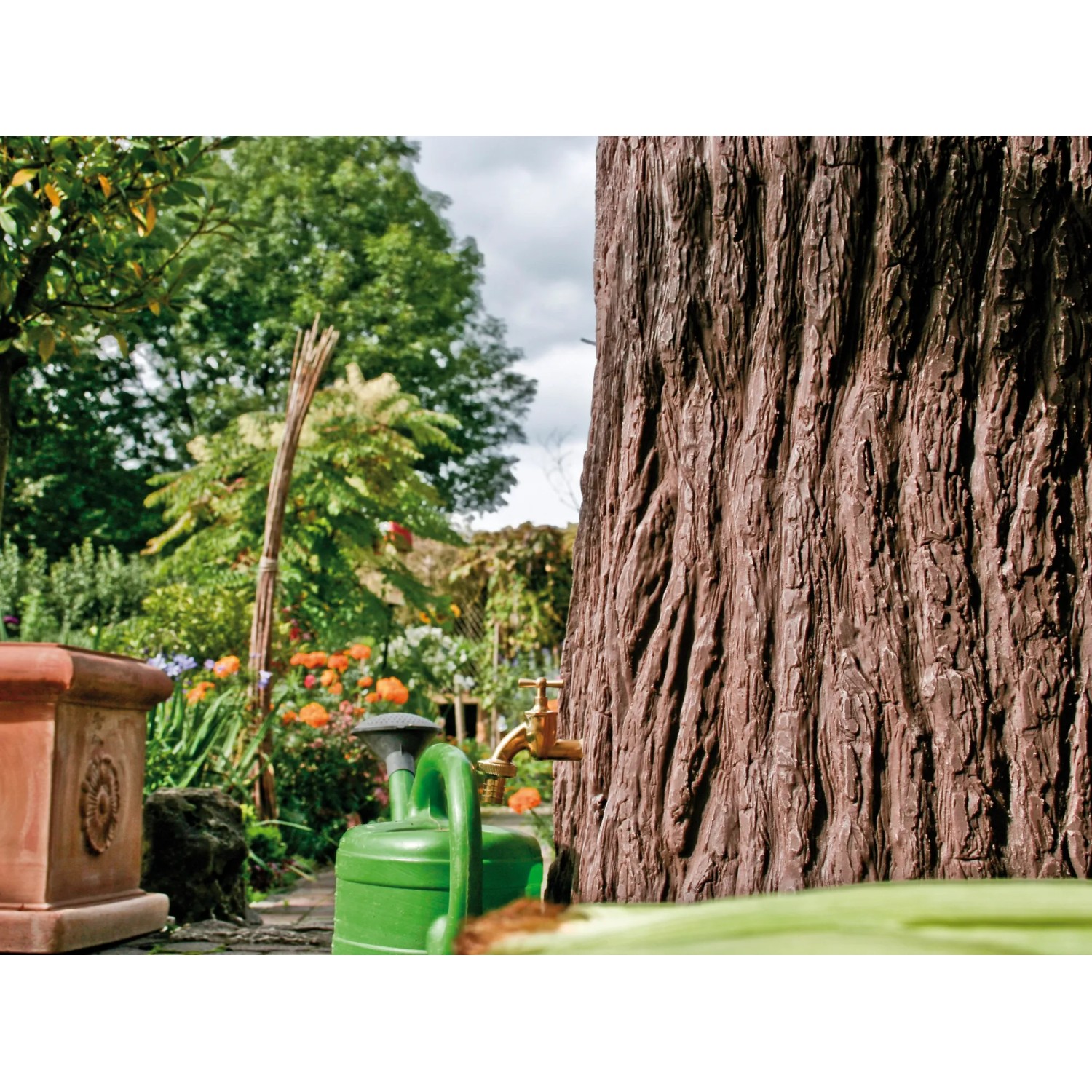 Dunkelbraune Arves Regentonne Evergreen 475 l in Baumstammoptik mit Wasserhahn im Garten.