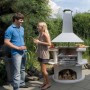 Buschbeck Grillkamin Venedig Weiß mit Edelstahlhaube im Garten mit zwei Personen.