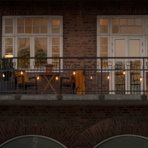 Konstsmide LED-Lichterkette mit bernsteinfarbenen Glühbirnen auf einem Balkon, stimmungsvolle Außenbeleuchtung.