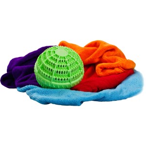 Grüner Steuber Wäscheball Purclean auf bunter Wäsche. Reinigungsmittel für saubere Textilien.