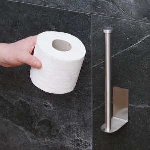 Silberner, selbstklebender Edelstahl Ersatzrollenhalter für WC-Papier an dunkler Wand. Hand hält Rolle.